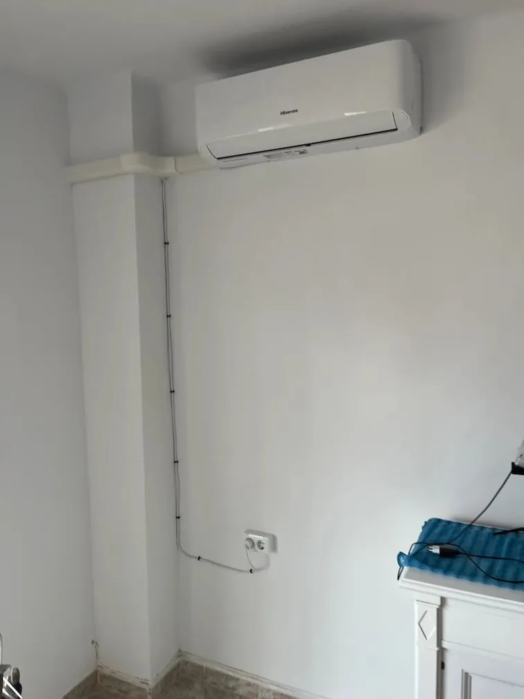 Split air conditioning unit on a bedroom wall, with cable trunking