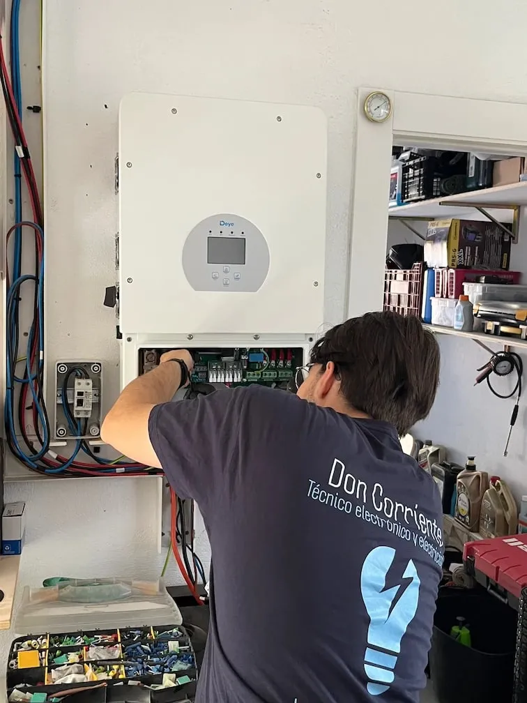 Don Corriente electrician, from behind, connecting a solar inverter