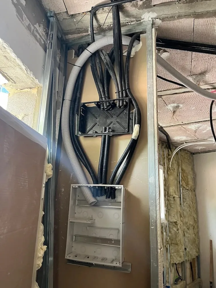 Consumer unit box set into a wall under construction, with the circuit conduits coming from the ceiling